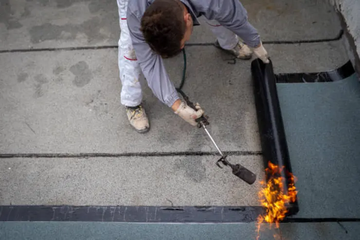 Worker applies heat to a waterproof membrane for roof.