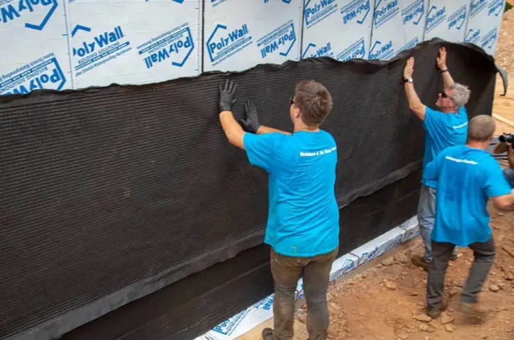 Workers install a moisture barrier for garage floor waterproofing in a new home.