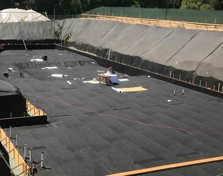 Waterproofing membrane installed across building foundation base.
